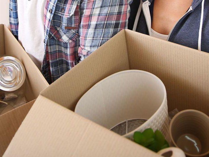 Household items being packed into a cardboard moving box