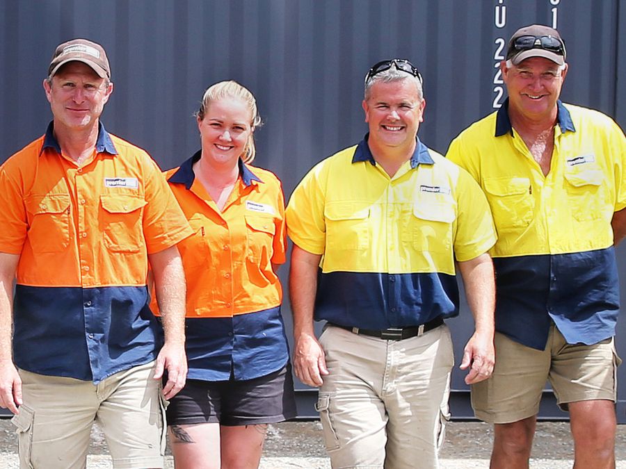 Four Premier Box team members in hi-vis shirts standing in front of a container