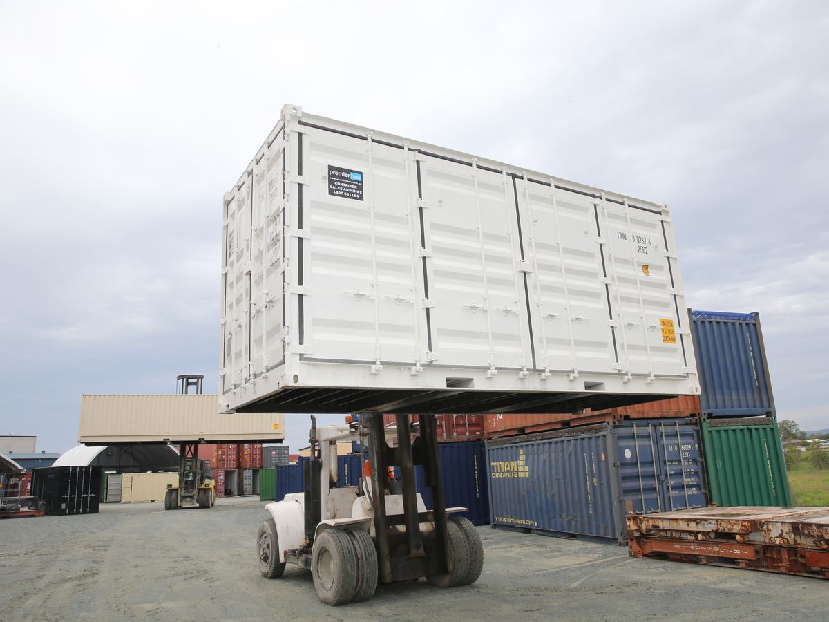 Forklift carrying a white side opening container across the yard