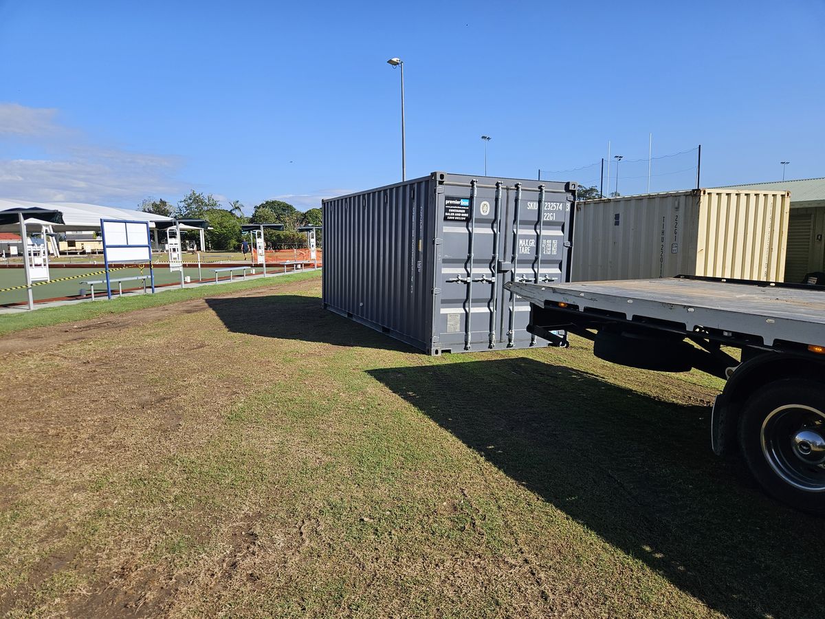 Hire container placed on a grassed customer site beside the delivery truck