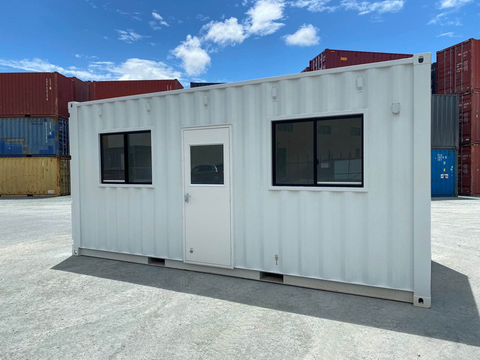 White container converted into a site office with a door and two windows