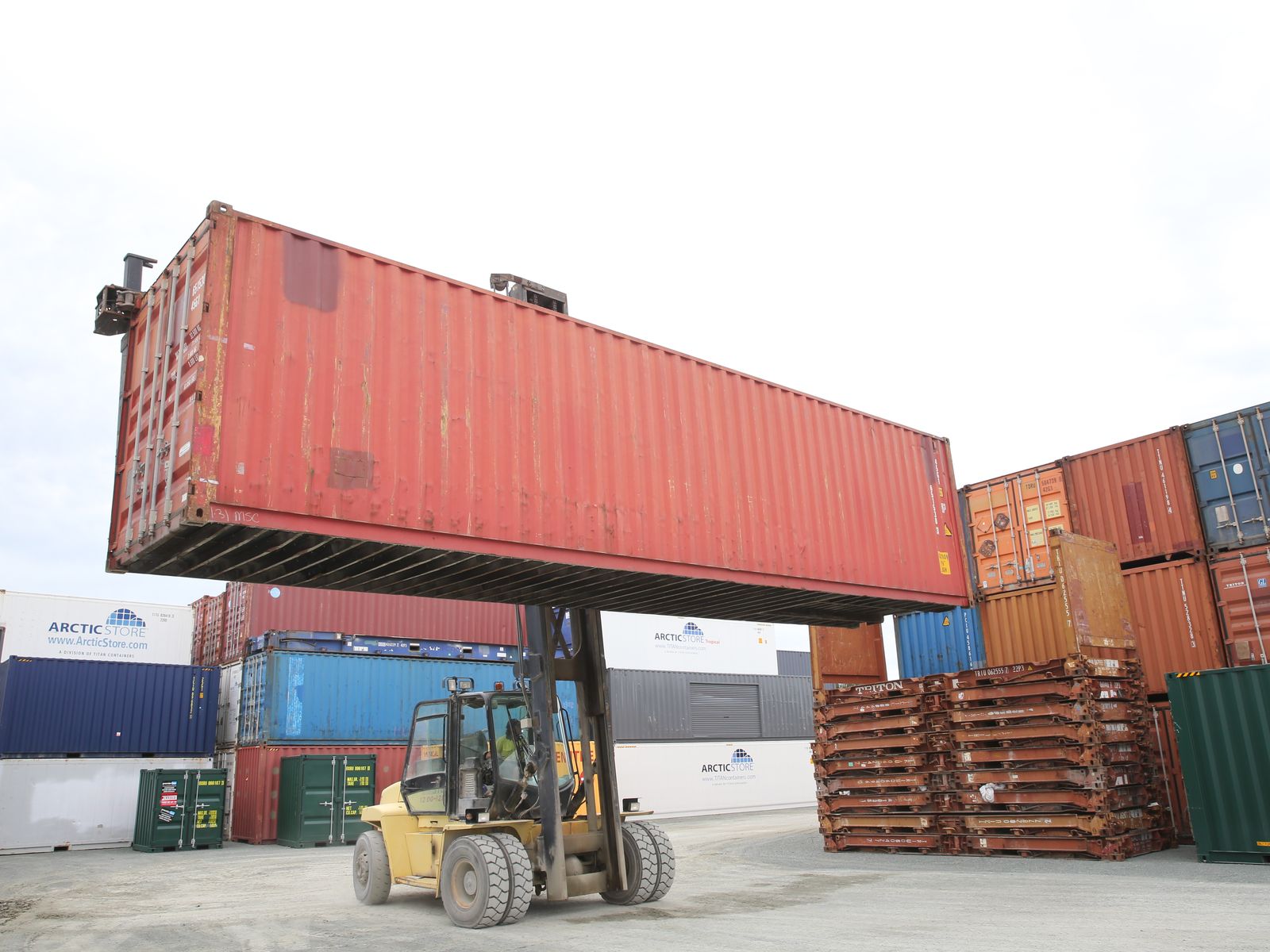 Red 40ft container being moved by a forklift in the container yard