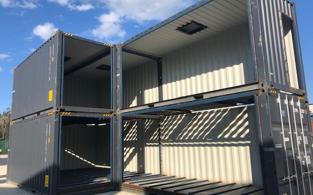 Stacked grey high cube containers forming an open two-level structure