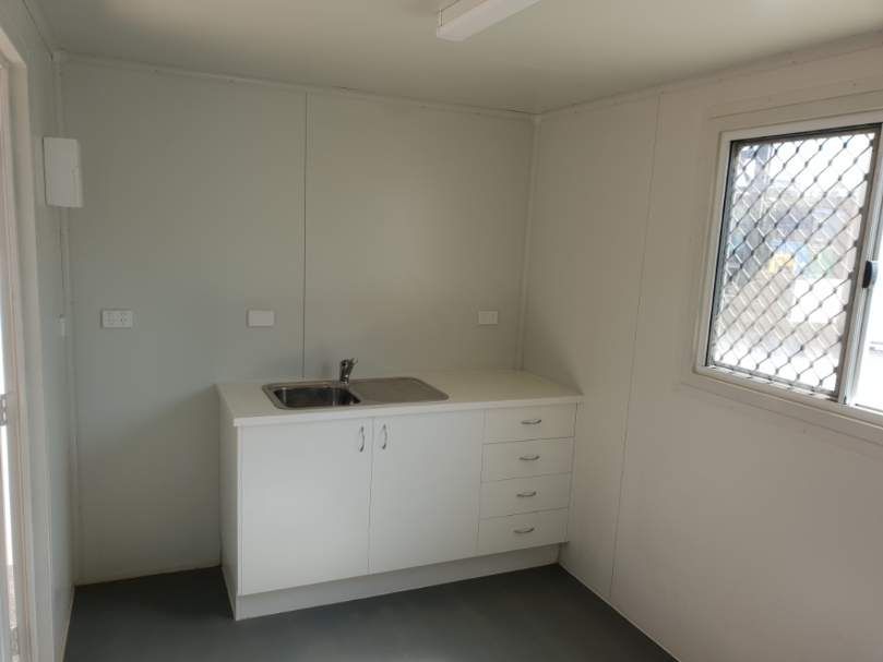 Container interior with a white kitchenette, sink and window