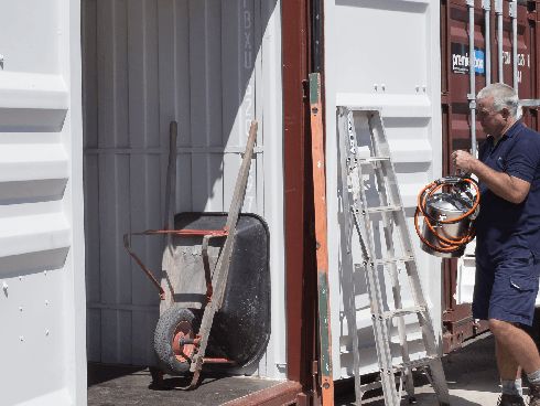 Customer loading a trolley and ladder into his storage container at the depot