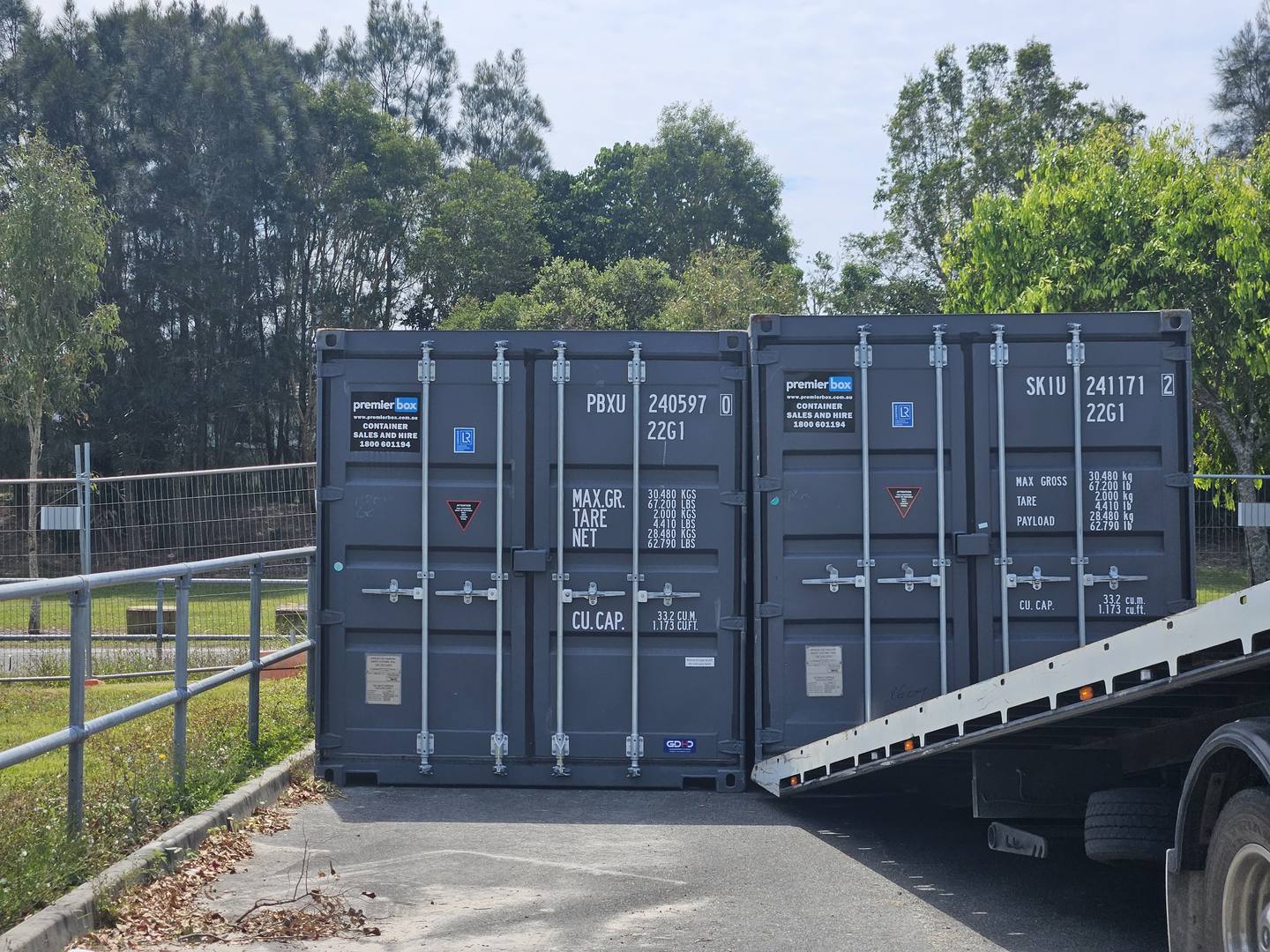 Two charcoal 20ft hire containers on a truck bed ready for delivery