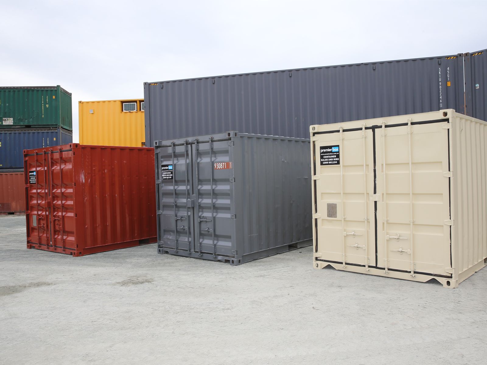 Red, grey and beige used 20ft containers side by side in the yard